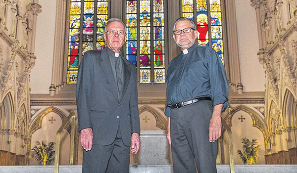 The outgoing rector of St. Joseph Cathedral, Father Peter Drilling, speaks to the new rector, Father Charles Slisz, about his new role. (Dan Cappellazzo/Staff Photographer)