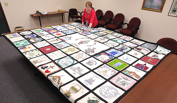 The Catholic Center's director of Central Services, Patricia Millemaci, looks over one of four panels that make up the Diocese of Buffalo's 150th anniversary quilt, created in 1997 by area parishes that donated panels representing their churches. (Dan Cappellazzo/Staff Photographer)