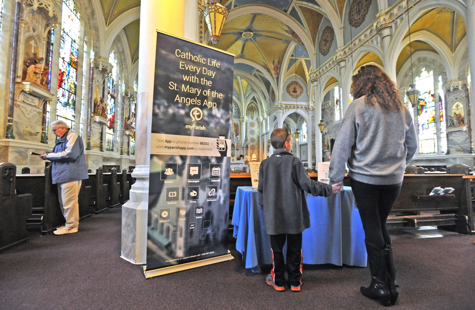 Area Catholics at St. Mary of the Angels Church, Olean, look over information on an app that parishioners can use to find Mass times, set confession appointments and reflect on readings. (Dan Cappellazzo/Staff Photographer)
