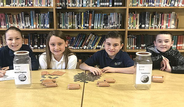 Fourth-graders Emily Jamieson (from left), Ella Haaseley, Samuel Todesco and Holdin Henderson, count quarters as part of St. Amelia School fund raiser for Catholic Charities. (Courtesy of St. Amelia School)