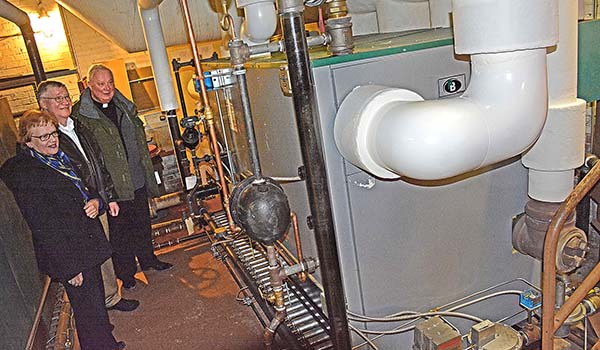 Father Richard Jedrzejewski, Assumption school board member Paul Kostyniak, and his wife, Carol Kostyniak, look over the new boiler in the basement of the Amherst Street church. The new boiler was purchased with a grant from Upon This Rock funds. (Dan Cappellazzo/Staff Photographer)