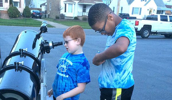 Evan Quinn looks through a telescope at the moon as part of a STREAM project. Also taking part in the project is Brandon Threet. (Courtesy of Mary Queen of Angels School)