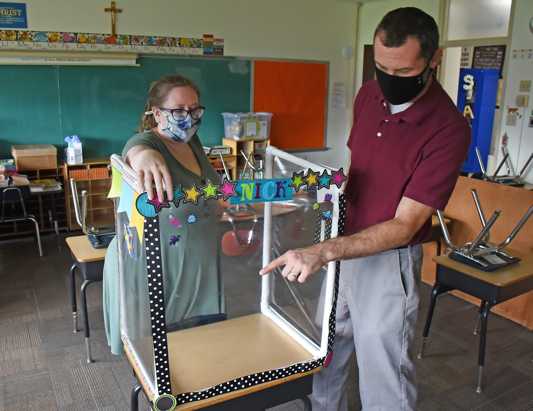 St. Amelia School principal Scott Kapperman and assistant principal Janet Larson look over a protective enclosure which will be provided for each student on their desk for the 2020 school year.