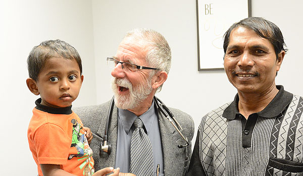 Dr. James Collins (center), chief medical officer for Mobile Primary Care, treats 6-year-old Nurhaliza Nazumia with his father, Ahmed Nazumia, at Catholic Charities Health Care Center, located on the Immigration and Refugee Assistance campus in Buffalo. The Nazumias are an immigrant family from Burma. (Patrick McPartland/Managing Editor)