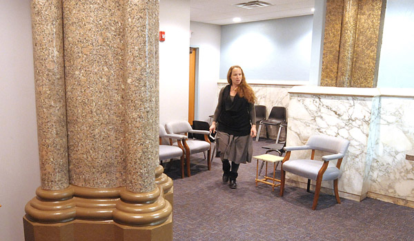 Framed by the original marble columns of the former Nativity Roman Catholic Church, Dr. Elizabeth Harding, MD at the new Catholic Charities Health Care Center walks through the medical area waiting room located in the former Nativity Roman Catholic Church at 10 Herkimer Street. Catholic Charities resettles up to 600 refugees per year and provides services up to an additional 400 immigrants annually at its West Side Campus. (Photo by Dan Cappellazzo)