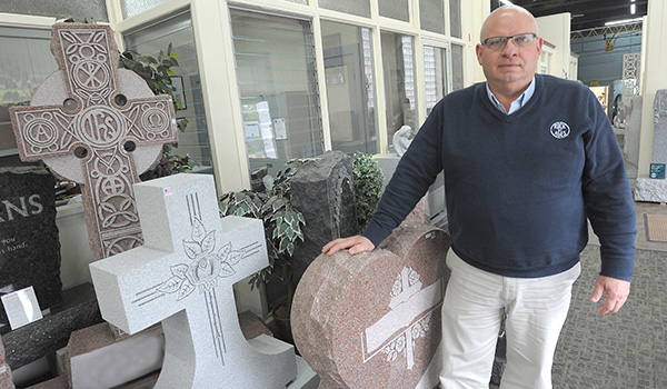Thomas Koch, president of Stone Art Memorial, shows families potential designs that can memorialize the deceased and his or her passions in life. (Dan Cappellazzo/Staff Photographer) 
