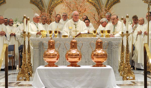 With three vessels of blessed olive oil at the foot of the altar, Bishop Richard J. Malone begins to bless the gifts at St. Joseph Cathedral during the annual Chrism Mass. (Dan Cappellazzo/Staff Photographer)
