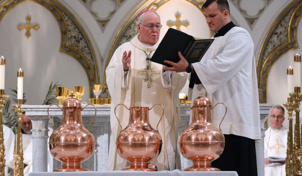 Secretary to the Bishop Father Ryszard Biernat assists Bishop Richard J. Malone as he blesses the sacred oils during the celebration of the Chrism Mass at St. Joseph Cathedral. (Dan Cappellazzo/Staff Photographer)