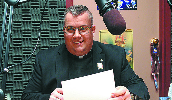 Father Jeffrey Nowak reads a public service announcement in the diocesan Office of Communications' radio studio. Father Nowak has been named this year's honorary chairperson of the Catholic Communications Campaign. (Dan Cappellazzo/Staff Photographer)