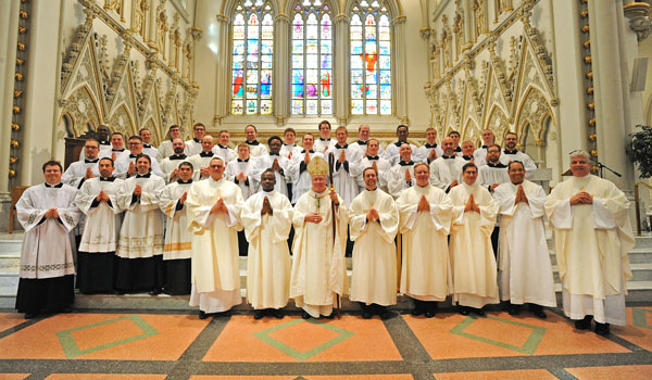 Deacons John Steiner Jr., Robert Agbo, Luke Uebler, Martin Gallagher and Cole Webster (from left front row in cream-colored robes) stand with Bishop Richard J. Malone (center) and other Buffalo clergy following their ordination Mass at St. Joseph Cathedral Saturday. (Dan Cappellazzo/Staff Photographer)