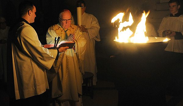 Bishop Richard J. Malone begins the Easter Vigil at St. Joseph Cathedral in darkness with the blessing of the fire. (Dan Cappellazzo/Staff Photographer)
