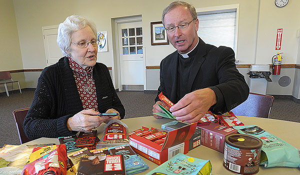 At St. John the Baptist Parish in Kenmore, volunteer Mary Grace and pastor Father Michael Parker organize Fair Trade products, which are sold after Mass to parishioners. (Dan Cappellazzo/Staff Photographer)