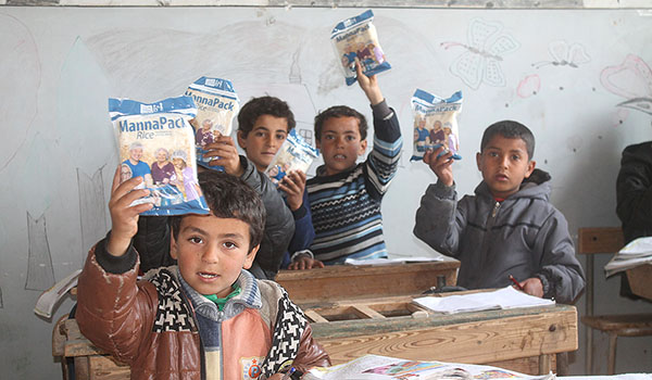 Children in Syria hold up their MannaPacks from Feed My Starving Children. The meal pouches, packed by volunteers, procide the needed nutrients for growing children. (Courtesy of Feed My Starving Children)