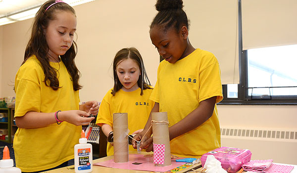 Second-graders Scarlett Zito (from left), Amiyah Callahan and Samantha Georger construct a tower during Gear Up at Our Lady of the Blessed Sacrament School, Depew. Their task is to design an object that can be pushed or pulled by a magnet. (Patrick McPartland/Staff Photographer)