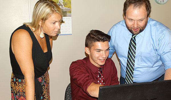 Adam Gorski, a Cardinal O'Hara High School senior, gets a little guidance in his writing from English teacher Jamie Wilczek (left) and athletic director Brian Lamping on his sports writing. Gorski has had his work published in several newspapers and websites. (Courtesy of Cardinal O'Hara High School)