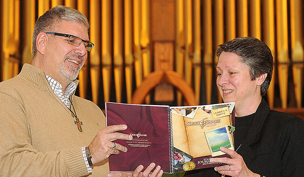 Deacon Greg Feary and Sister Joyce King, CSSF, look at the GriefShare workbook at Our Lady of Pompeii Parish. The book, along with a DVD series, helps those who are coping with the loss of a loved one. (Dan Cappellazzo/Staff Photographer)