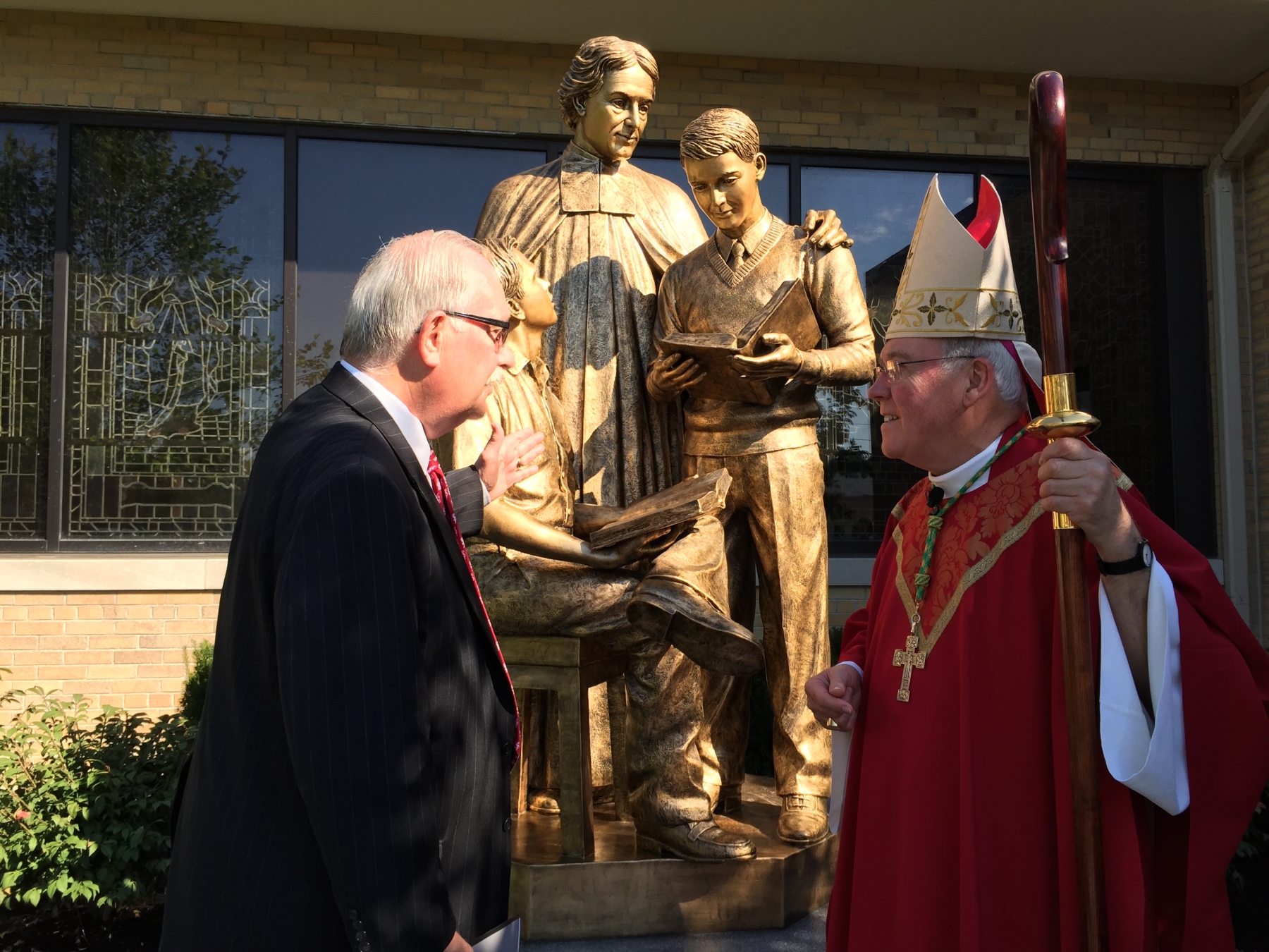 St. Joseph's Collegiate Institute President Robert Scott shows Bishop Richard J. Malone the new statue dedicated to the school's founder, St. John Baptist de La Salle. 