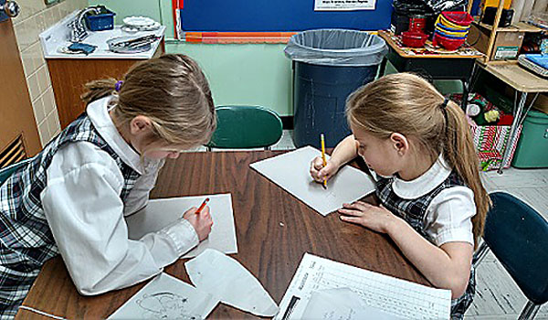 Third-graders Claudia Giallella (left) and Nadia Rodemeyer work on their self-portraits for the community art mosaic. (Courtesy of Immaculate Conception School)