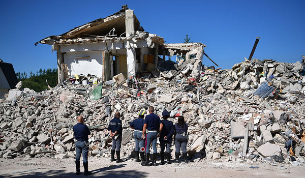 Police officers view the remains of a building that was destroyed during an earthquake, on August 25, 2016 in Amatrice, Italy. The death toll in the 6.2 magnitude earthquake that struck around the Umbria region of Italy in the early hours of Wednesday morning has risen to at least 247 as thousands of rescuers continue to search for survivors. (Photo by Carl Court/Getty Images)