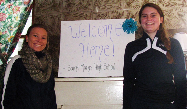 Senior Tia Piotrowski (left) and junior Kendra Ciezki stand with the sign they placed on the mantel of the home they helped refurnish. (Courtesy of St. Mary's High School)
