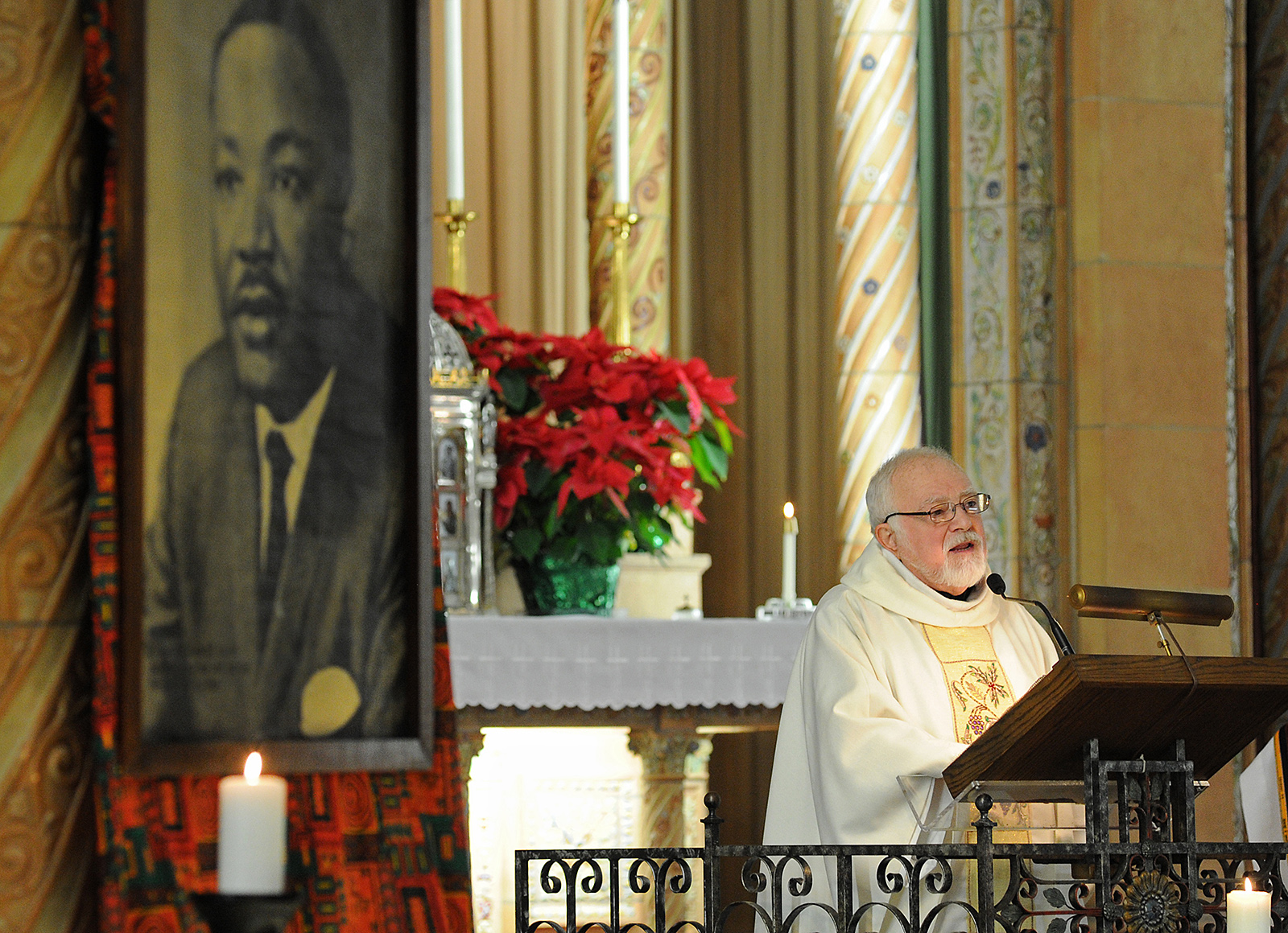 Framed by a portrait of Dr. Martin Luther King Jr., guest homilist Reverend James Loiacono, OMI, spoke at a service honoring Dr. King at Blessed Trinity Church. about the legacy of faith and love that Dr. King spoke of. Loiacono, was involved in the Civil Rights Movement in Buffalo int he 1960's, about the legacy of faith and love that Dr. King preached in the 1950's and 60's.
(Dan Cappellazzo/Staff photographer)