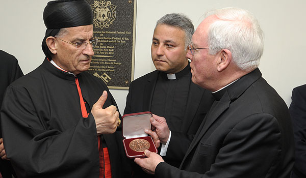Maronite Patriarch Moran Mor Bechara Boutros al-Rahi (left) presents Bishop Richard J. Malone (right) with a medal showing the patriarchal coat-of-arms on one side and depiction of Mary in the holy valley of Qannubin in Lebanon on the reverse. Both met at St. John Maron Church in Williamsville. Father Elie G. Kairouz (center) is pastor at St. John Maron. (Patrick McPartland/Staff Photographer) 