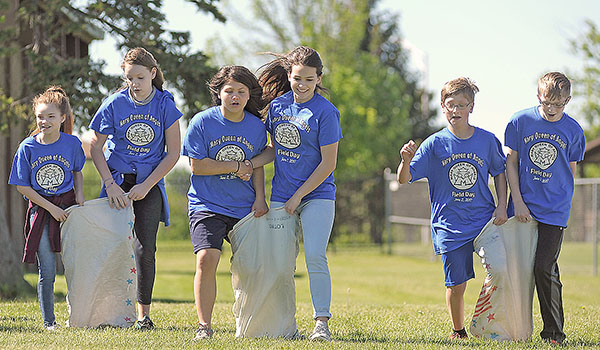 Mary Queen of Angels School eighth-graders participate in a sack race during a field day for teachers, students and families on Friday, June 2 at Cheektowaga Town Park. This is the last group of kids who will attend the school, as it is closing its doors for good. (Dan Cappellazzo/Staff Photographer)