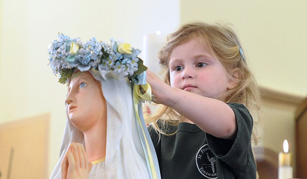 Three-year-old Lilly Colwell places a flower crown on the Blessed Virgin Mary as children from St. Francis of Assisi Early Childhood Center participate in a May Crowning at the church in Tonawanda. (Patrick McPartland/Staff Photographer)