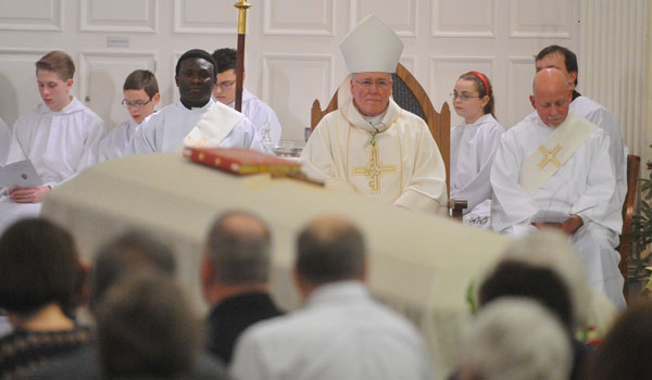 Bishop Richard J. Malone looks on the casket of Bishop Bernard J. McLaughlin during a special memorial Mass at St. John the Baptist Parish in Kenmore on Thursday night. (Patrick McPartland/Staff Photographer)