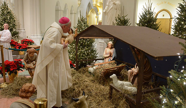 Bishop Malone kisses the Baby Jesus at the beginning of St. Joseph Cathedral's midnight Mass on Christmas. (Photo by Patrick McPartland/WNY Catholic)