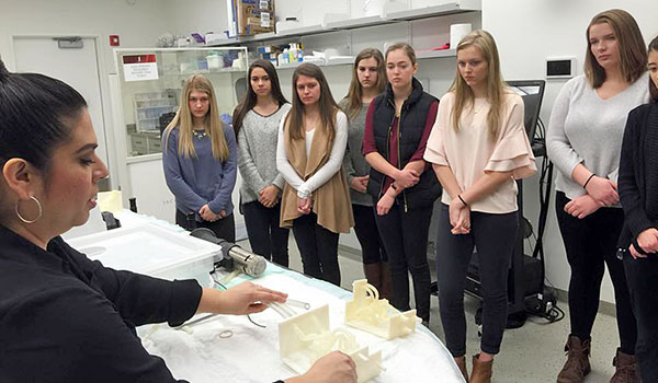 Mount Mercy students listen to an explanation about the 3D-printed vascular flow models at the Jacobs Institute. Students had the opportunity to handle the models and practice in the advanced patient-specific, catherization simulator lab. (Courtesy of Mount Mercy Academy)