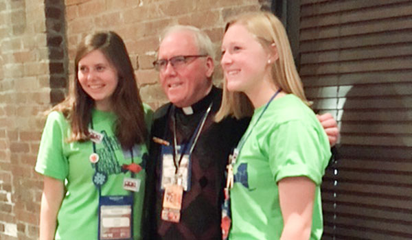 Lauren Nelson and Caroline Franczak, from Our Lady of Lourdes Parish in Bemus Point, pose with Bishop Richard J. Malone after adoration at Lucis Oil Stadium in Indianapolis during the National Youth Conference. (Courtesy of Kathy Nicastro)