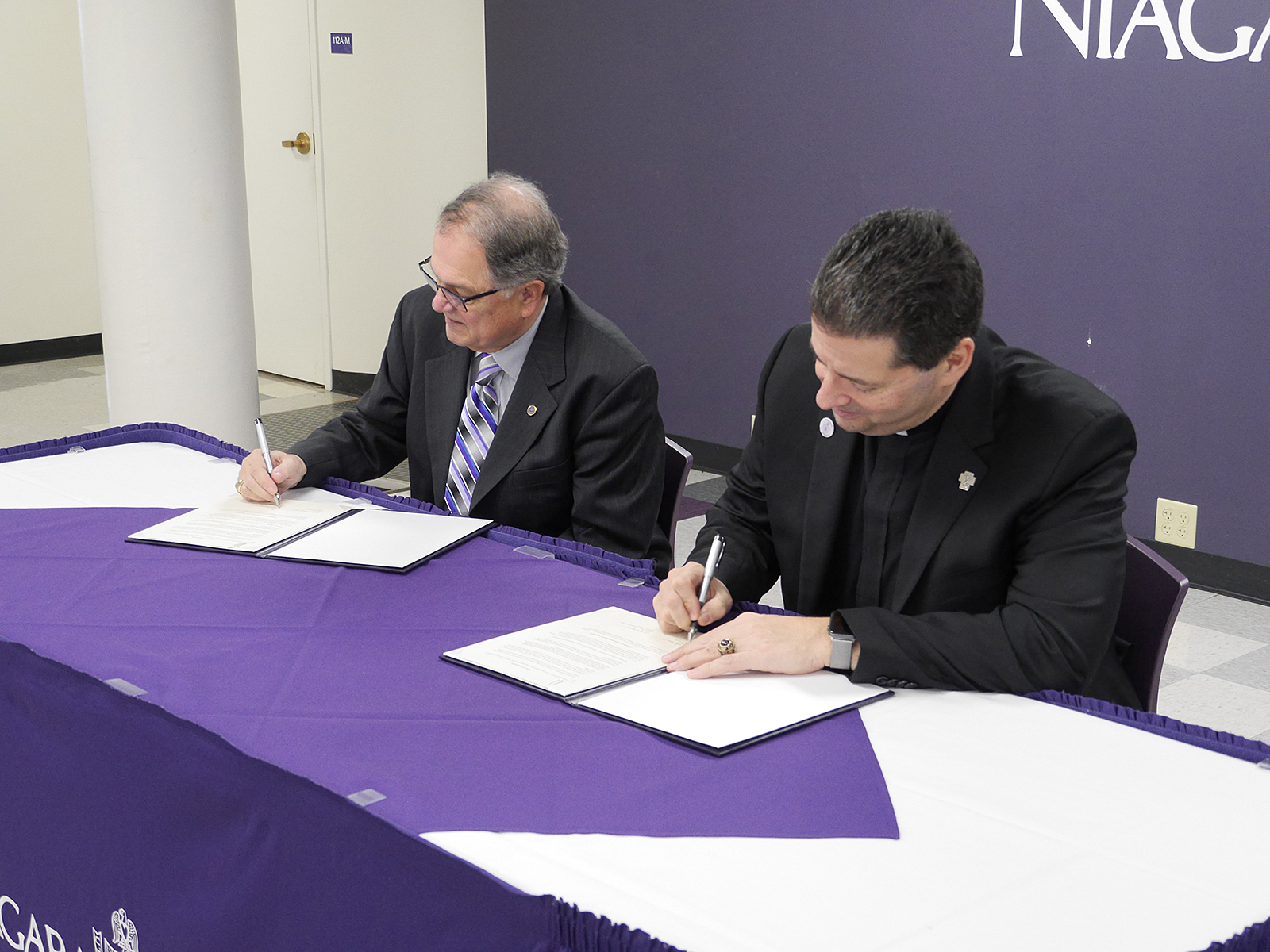 Dr.  William Murabito, president of Niagara County Community College, and the Father James J. Maher, CM, president of Niagara University, sign an agreement to formalize a public/private partnership that will enable the two institutions to provide service, research, and education to support and enhance postsecondary education outcomes and community impact in the Niagara community.
(Courtesy of Niagara University)