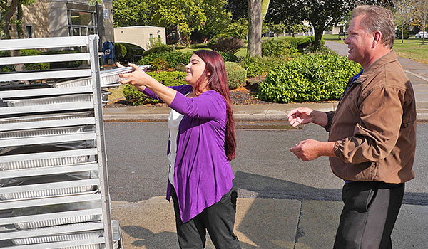 Nicole Slipko, catering manager for the Metz Culinary Management operation at Niagara University, helps Grant Babcock, operations manager of Community Missions of Niagara Frontier, load trays of food that will be given to guests of the service agency and the Heart, Love and Soul food pantry and dining room. (Courtesy of Niagara University)