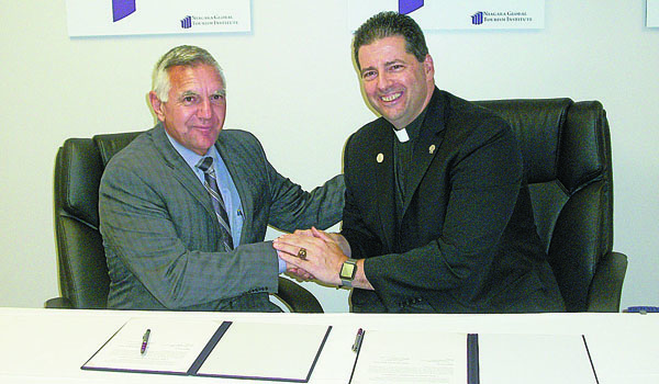 Joseph A. Ruffolo, president and CEO of Niagara Falls Memorial Medical Center, and Father James J. Maher, CM, president of Niagara University, shake hands after signing a memorandum of understanding between their two organizations for future partnership. (Kimberlee Sabshin/Staff)