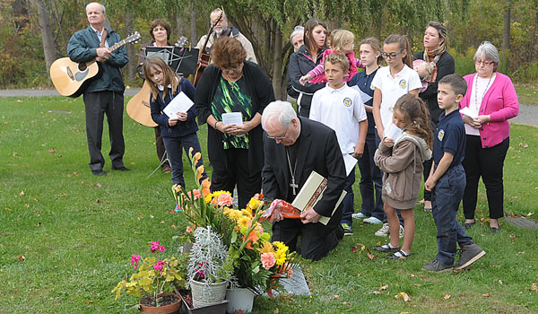 Bishop Richard J. Malone lays flowers at the grave of baby Jesse during the observance of National Remembrance Day of the Unborn at St. Mary Cemetery in Dunkirk
(Patrick McPartland/Staff Photographer)