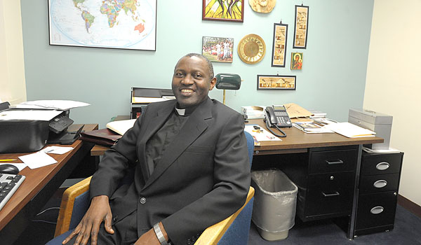 Father Justus Ndyamukama sits in his office at the Catholic Center in Buffalo. (Patrick McPartland/Staff Photographer)