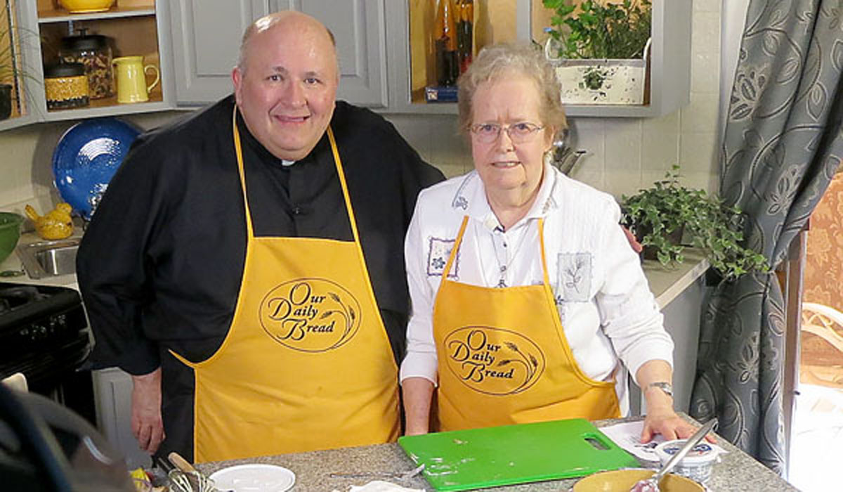 Father Paul D. Seil learns about three different parish communities committed to putting their faith into action.  In the kitchen is Sister Mary Ann Butler, SSJ representing Nativity of the Blessed Virgin Mary parish in Harris Hill.