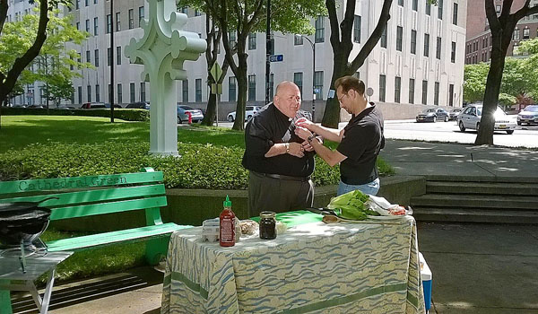 Daybreak's Engineer Technician, Peter F. Herrmann adjusts Fr. Paul D. Seil's microphone, at St. Joseph Cathedral Park in downtown Buffalo prior to recording an episode of Our Daily Bread.
(Courtesy of Daybreak TV)