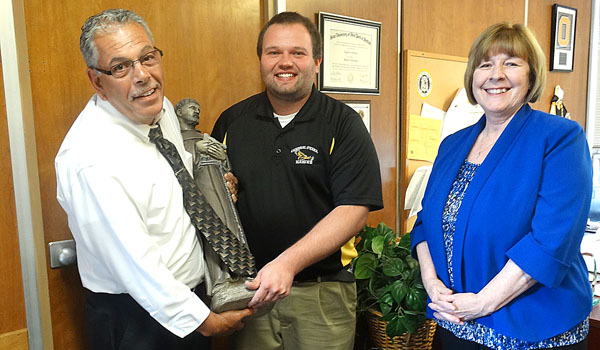 Angelo Sciandra, left, long-time athletic director at Cardinal O'Hara High School, hands over `Frank,` a statue of St. Francis of Assisi and symbol of the athletic department, to Brian Lamping (center), newly-named athletic director. Principal Mary Holzerland (right), congratulates them both. The statue has been placed near the flagpole on the school's athletic field for the past 10 years, and Sciandra recalled that in all that time, there has never been a serious injury in any competition. 