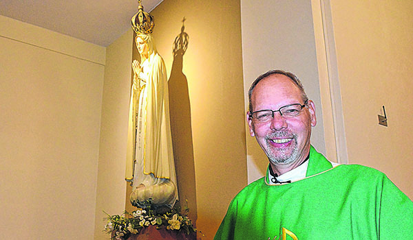 Father Robert Zilliox stands before the statue of Our Lady of Fatima located at Sacred Heart of Jesus Church and Shrine in Bowmansville. Created by sculptor José Thedim, the statue is a prototype for the pilgrim statues that traveled to the Americas in 1947. (Patrick McPartland/Managing Editor)
