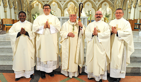 Bishop Richard J. Malone (center) stands with new priests Father Peter Bassey, Father Paul Cygan, Father Peter Santandreu and Father Gerard Skrzynski after a Mass at St. Joseph Cathedral where the four men were ordained into the priesthood. (Dan Cappellazzo/Staff Photographer)