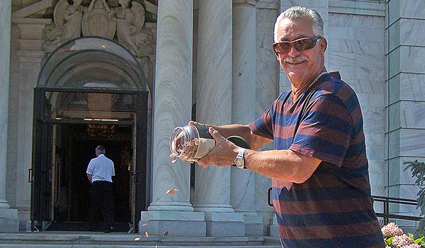 Carl Amorosi drops a jarful of pennies onto the sidewalk of Our Lady of Victory Basilica as part of the Lackawanna church's annual Pennies to Heaven event. The penny drop, along with carnival games and barbecued chicken, marked the annual Father Baker's Pennies to Heaven chicken barbecue and family carnival. (Patrick J. Buechi/Staff)