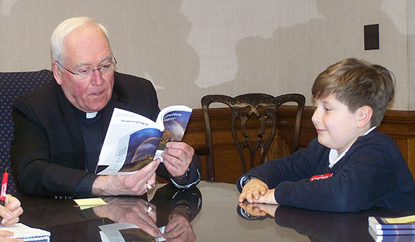 Bishop Richard J. Malone receives a prayer book from Ethan Franz, a fourth-grader at St. John the Baptist School in Kenmore. The parishioners of St. John's collected their favorite prayers for a `An Invitation to Prayer.` (Patrick J. Buechi/Staff)