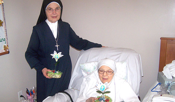 Sister M. Ambrogia Alderuccio helps Sister Elena Sinatra show off her handmade silk lilies. Despite her poor health, Sister Elena continues to serve her community in any way she can. (Patrick J. Buechi/Staff)