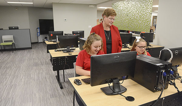 Retires St. Peter's teacher Sandy Jordan works with students Melissa and Lily Dipasquale inside the new media center. The center was dedicated to Jordan for her 40 years as the school's librarian and technology director. (Patrick McPartland/Managing Editor)