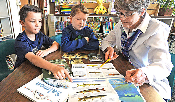 Polly Lougen, a science teacher at St. Mary School in Swormville, and fourth-grade students Dylan Leong and Derek Ogiba speak in the school library about the fish the class raised from eggs. Once they were old enough, the young fish were then released into Glen Park's Ellicott Creek in Williamsville. (Dan Cappellazzo/Staff Photographer)