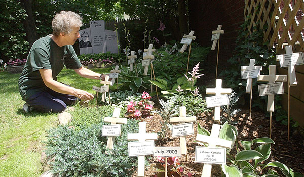 Sister Karen Klimczak, SSJ, arranges some of the small crucifixes in the Peace Garden at Bissonette House in Buffalo. (Patrick McPartland/Staff Photographer)