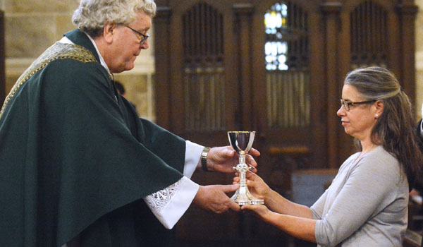 Carolyn Scaglione, a descendant of Father John Hamel, first pastor of St. Mary of the Angels, hands Father Hamel's refurbished chalice to its current pastor, Father Gregory Dobson, during a Mass celebrating the parish's 140th anniversary. Scaglione is the great-great-great niece of Father Hamel. (Patrick McPartland/Managing Editor)