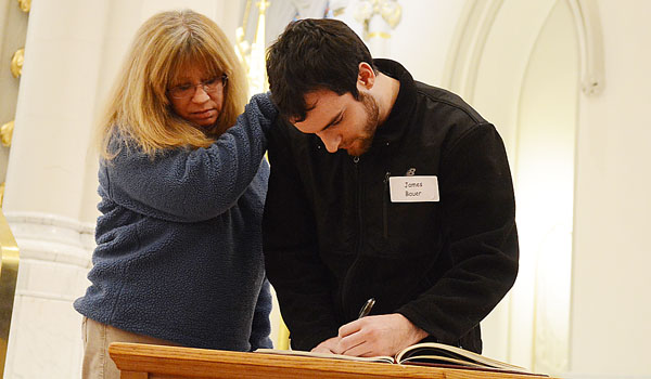 The Elect, James Bauer (left) and his sponsor, Bonnie Schiffmaker, sign the Book of the Elect at the Rite of Christian Initiation of Adults Mass at St. Joseph Cathedral in Buffalo. (File Photo)